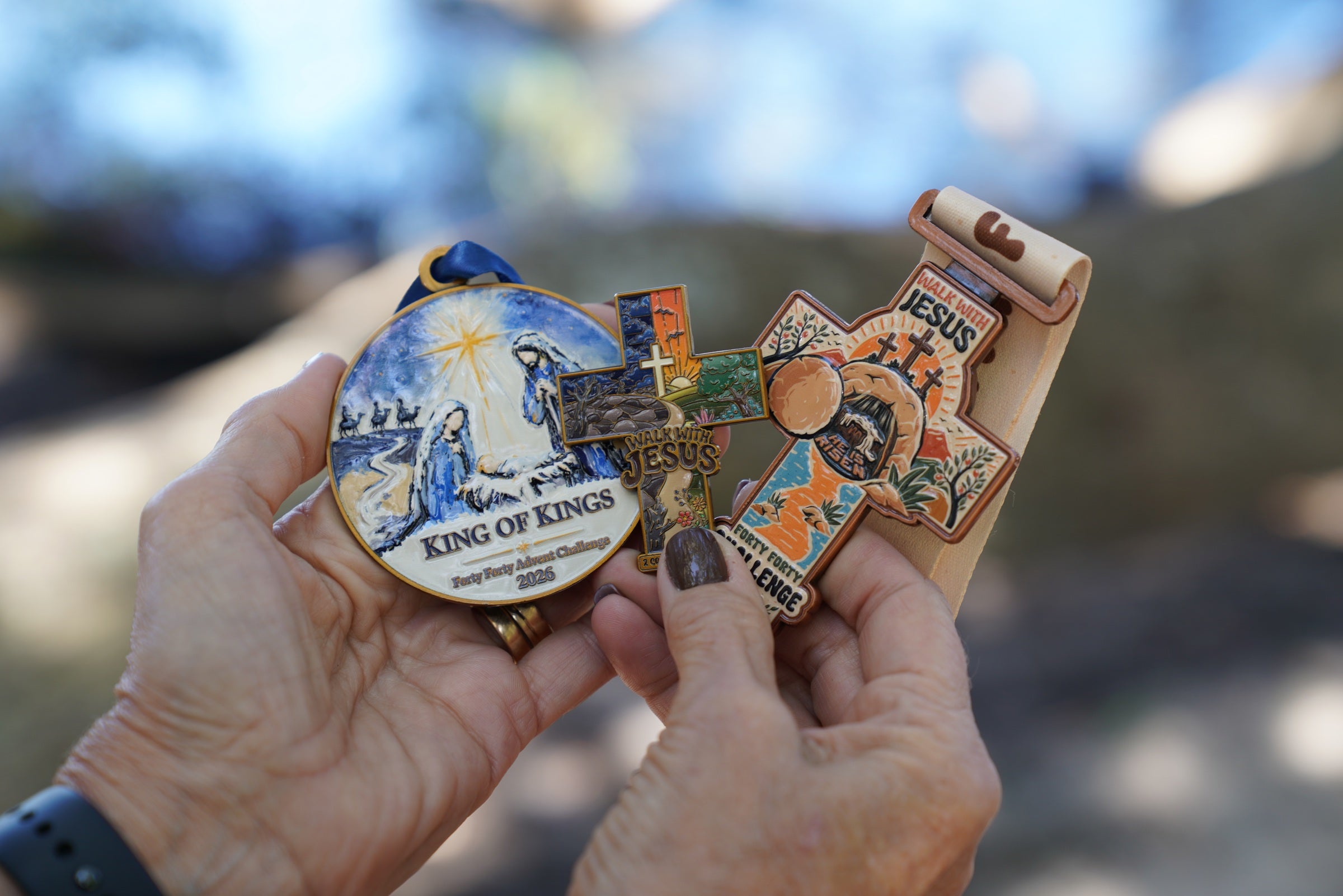 Hands holding the Advent ornament, Made New pin and Forty Forty Easter medal together